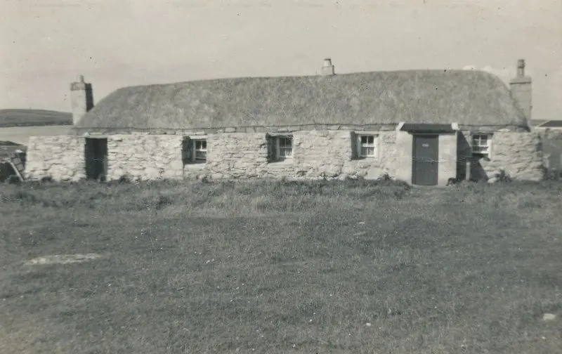 Old black-and-white photograph of a thatched stone blackhouse