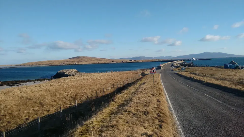 The single-track road running towards the causeway, with the sea and the hills of North Uist ahead