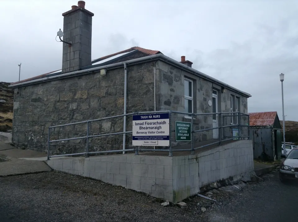 Berneray Visitor Centre, a stone building with a ramp and a sign by the harbour road